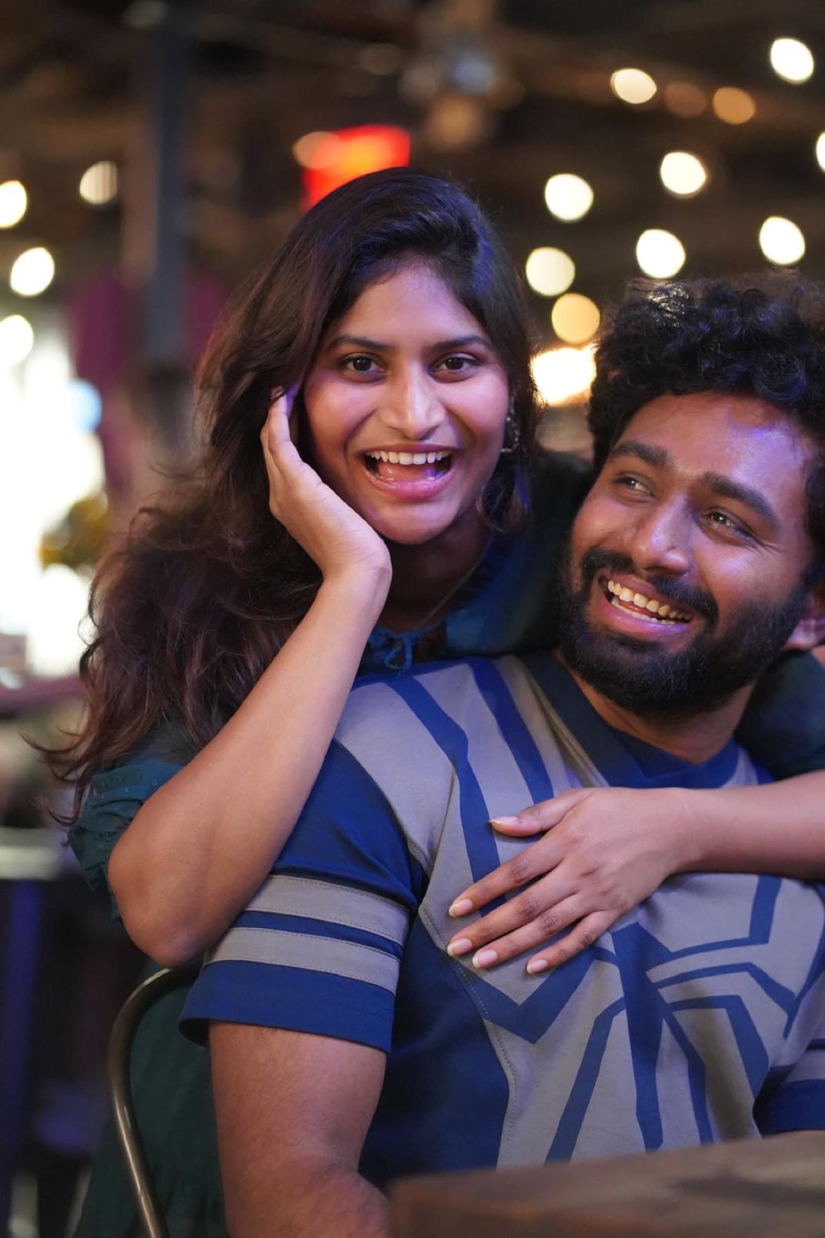 Tejesh & Madhu Padisetti laughing together under string lights