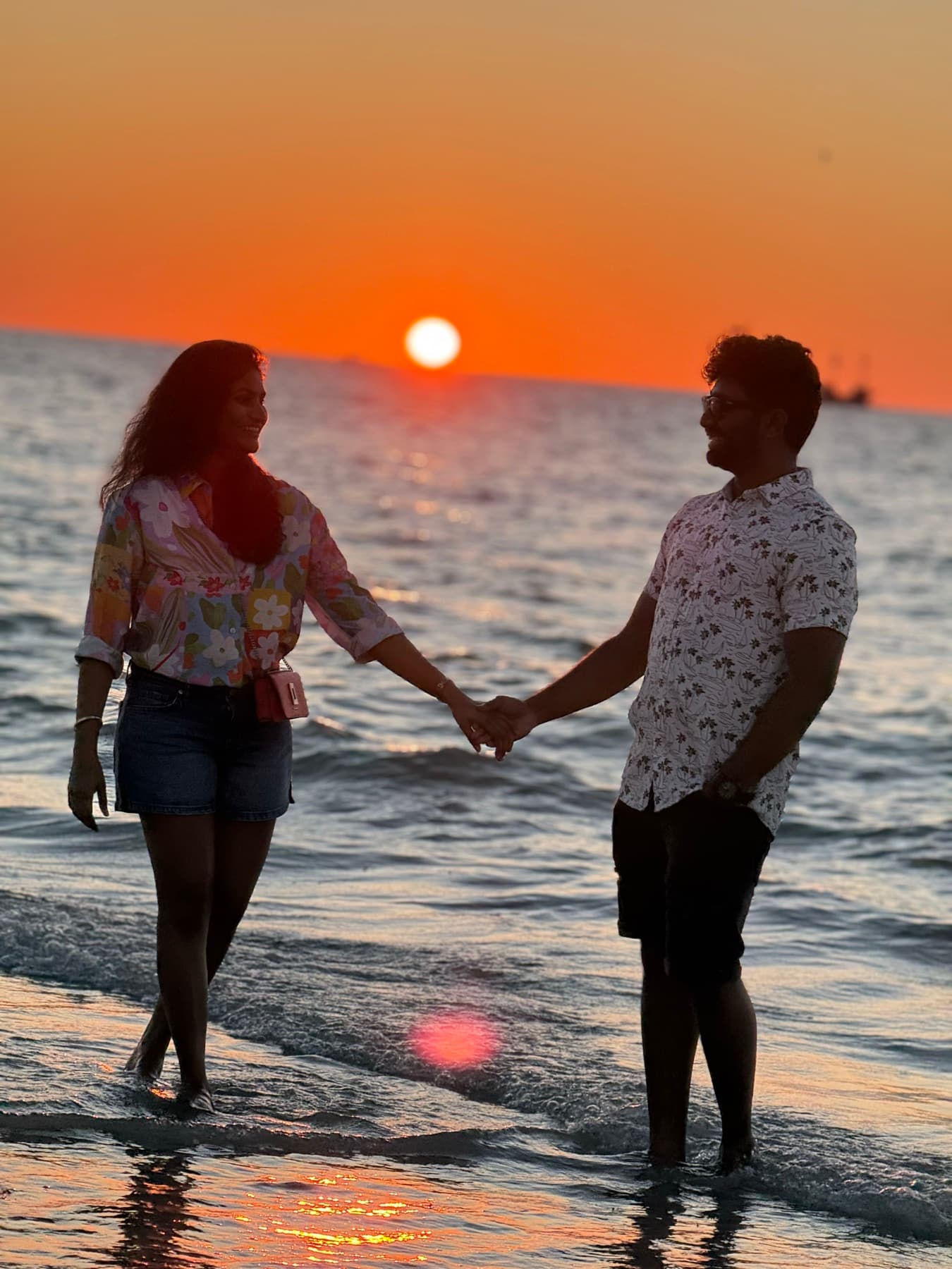 Tejesh & Madhu Padisetti silhouetted by the ocean at sunset
